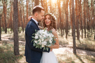 Newlywed couple standing in forest