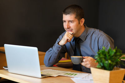 Young man using mobile phone while sitting on table