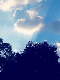 Low angle view of silhouette trees against blue sky