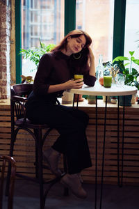 Woman with eyes sitting at table in restaurant