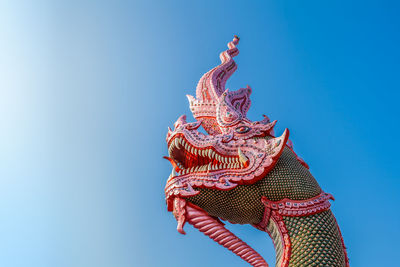 Low angle view of dragon statue against blue sky