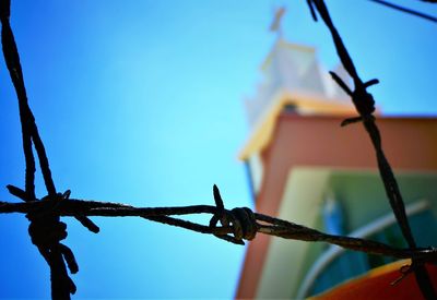 Low angle view of barbed wire against clear blue sky