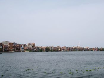 Sea by buildings against clear sky