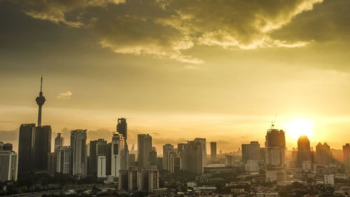 View of skyscrapers in city against sunset sky