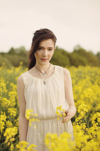 Portrait of young woman standing on field