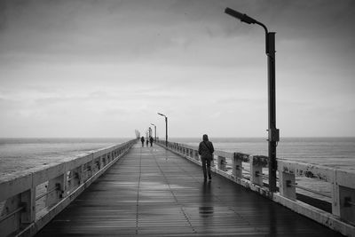 People walking on pier against sky