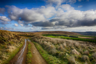 Road amidst field against sky