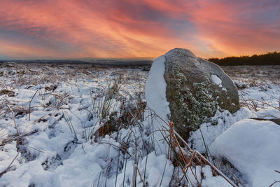 Frozen lake against sky during sunset