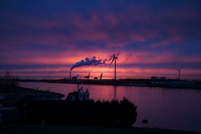 Silhouette smoke emitting from factory against sky during sunset