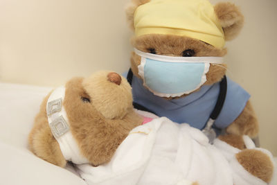 Close-up of stuffed teddy bears on bed against wall