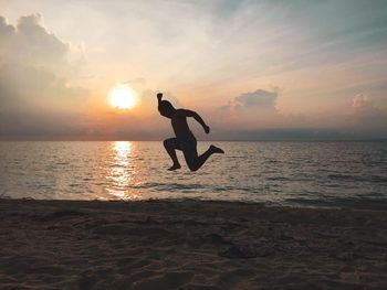 Silhouette person on beach against sky during sunset