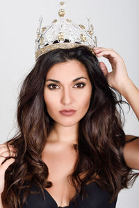 Portrait of beautiful model wearing crown against white background