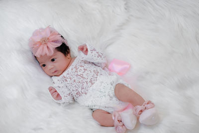 Cute newborn baby with pink bow tie sleep on white fluffy coverlets