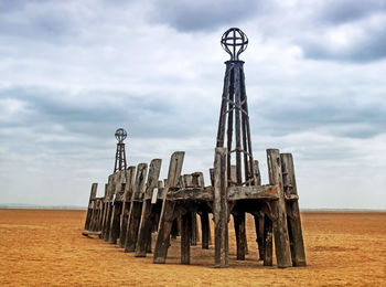 Wooden posts on beach against sky