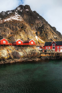 Houses by lake and mountains against sky