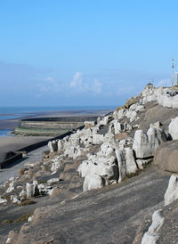 Scenic view of rocks on beach against blue sky