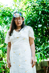 Portrait of young woman standing against plants