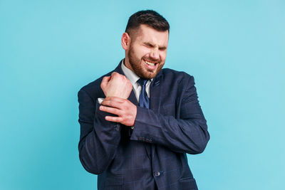 Man holding wrist against blue background