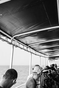 Rear view of man and woman sitting in sea against sky