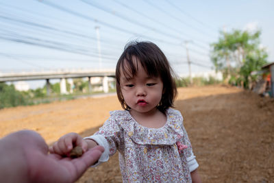 Baby girl giving stone to person on field