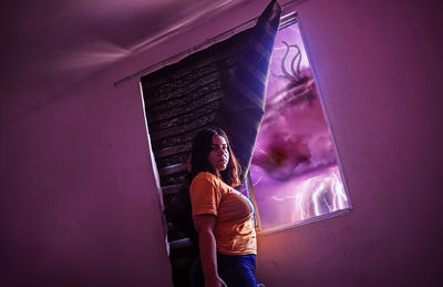 Woman standing by window against building