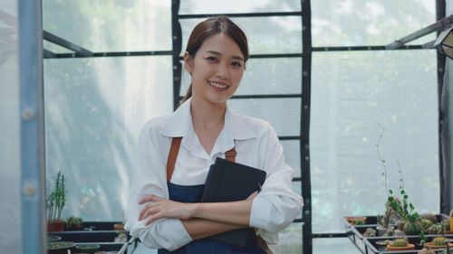 Portrait of a smiling young woman standing against window