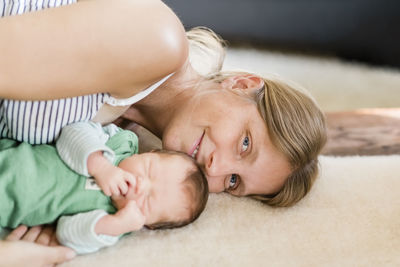 Portrait of mother with new born baby lying on bed at home