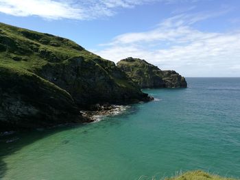 Scenic view of sea by cliff against sky