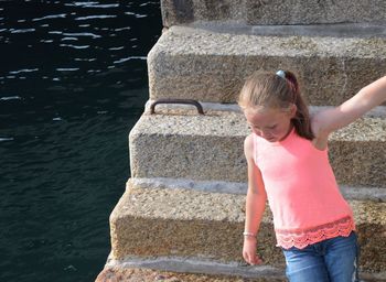 Full length of young girl standing against stone wall