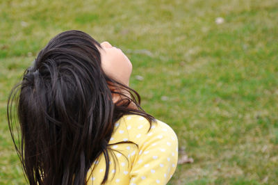 Side view of girl looking up against grassland
