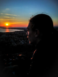 Portrait of man looking at sea against sky during sunset