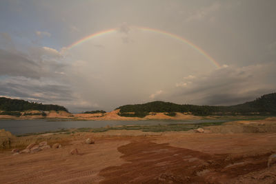 Scenic view of rainbow over landscape against sky