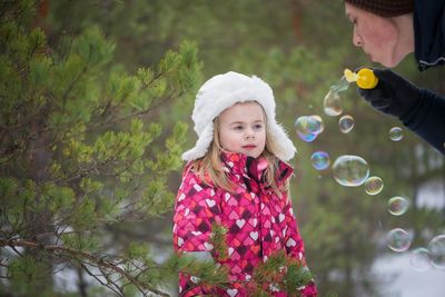 Daughter looking at mother blowing bubbles