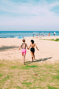 Rear view of women walking together on beach