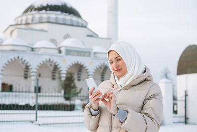 Midsection of woman holding smart phone in snow