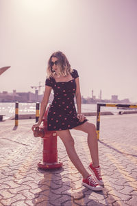 Low angle view of woman leaning on water pump against sky