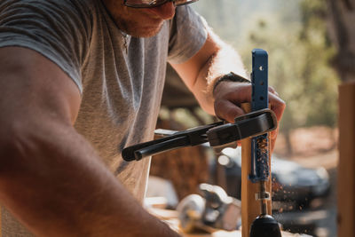 Man wood working using a drill and clamp with dust flying