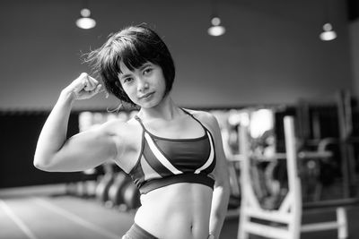 Portrait of young woman standing against blurred background