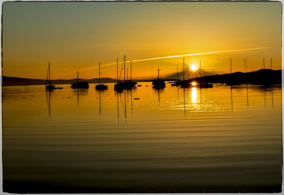 Silhouette boats moored on sea against sky during sunset