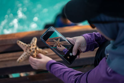 Female taking picture of a starfish on the tropical sea deck.