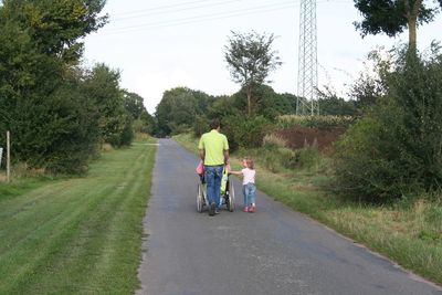 Rear view of mother and daughter walking on road