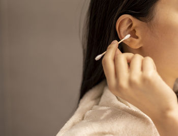 Woman cleaning her ear with a cotton swab after taking a shower