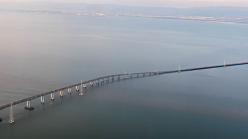 Bridge over calm sea against sky