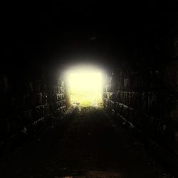 Illuminated tunnel against buildings