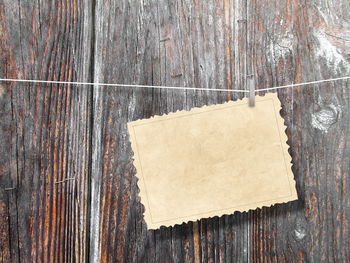 Close-up of paper hanging on string against wooden wall