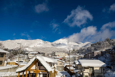 Houses and snowcapped mountains against blue sky