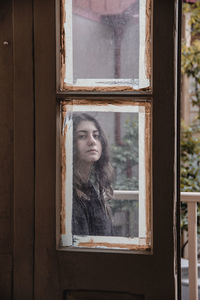 Portrait of woman looking through window