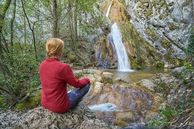 Man sitting on rock in forest