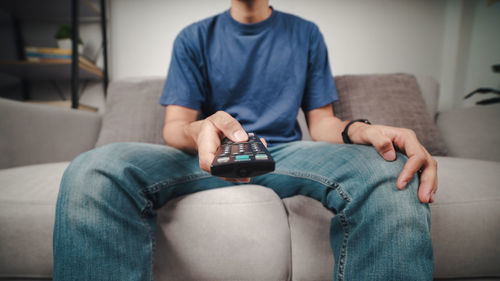 Midsection of man sitting on sofa at home