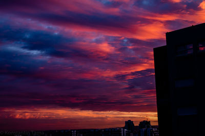 Silhouette buildings against dramatic sky during sunset